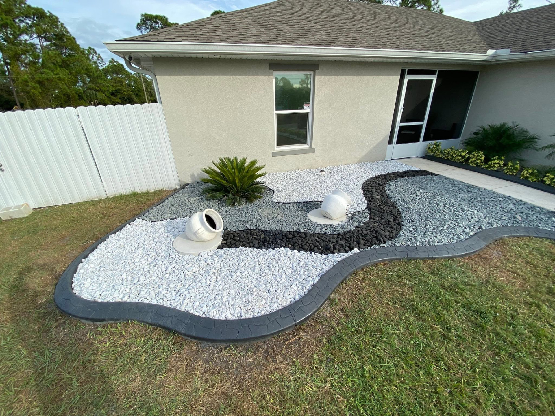 Black curbing outlining a designer white, gray and black rock garden