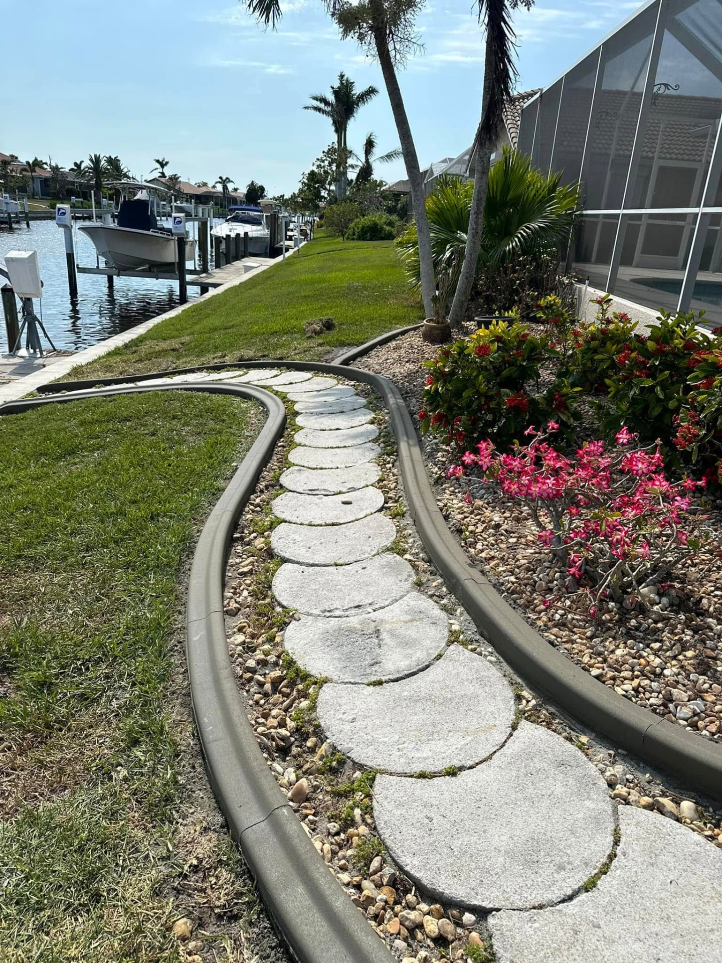 Gray curbing winding along a round stepping stone path beside a canal dock