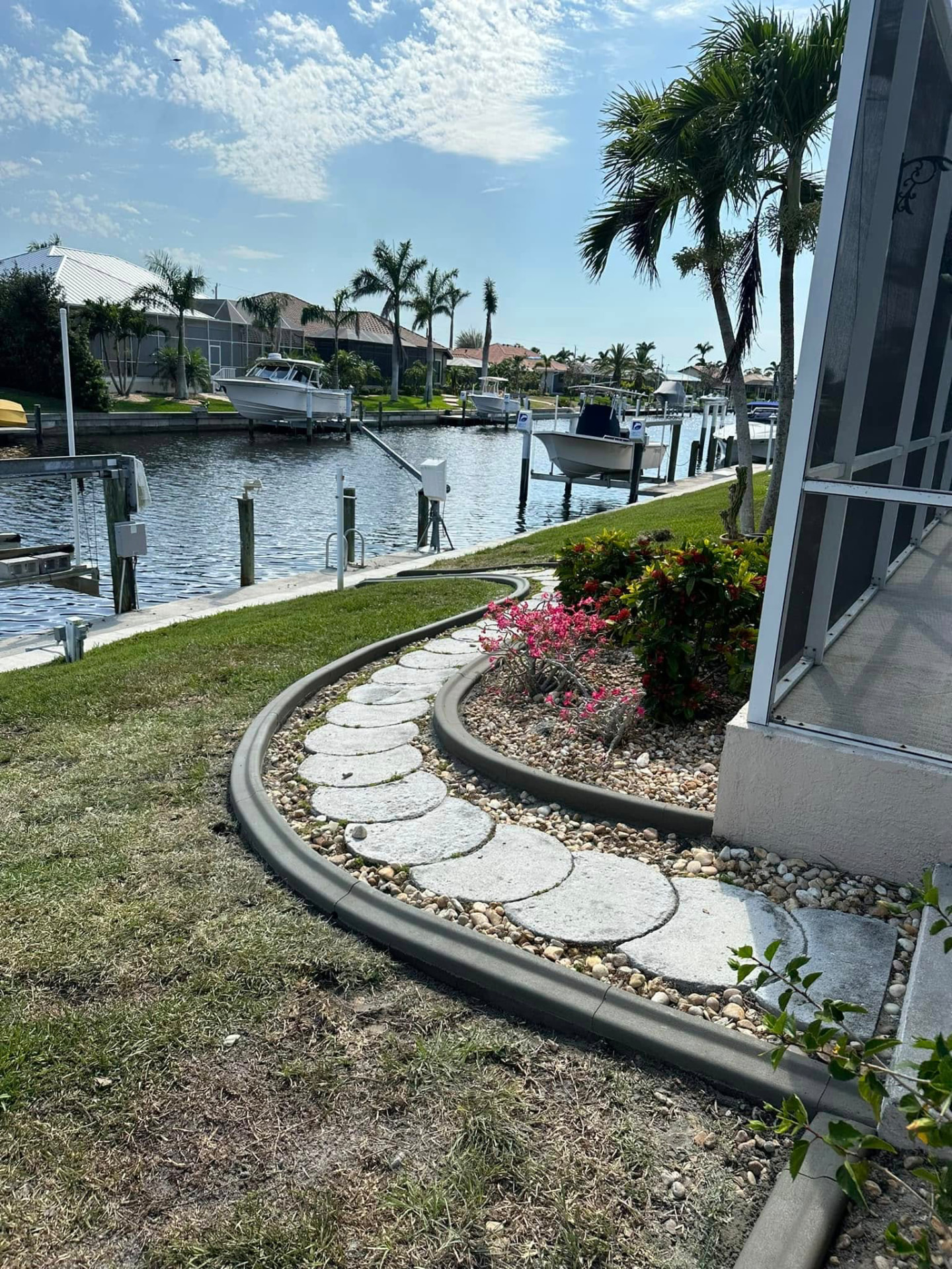 Charcoal curbing framing a stepping stone path along a Southwest Florida canal