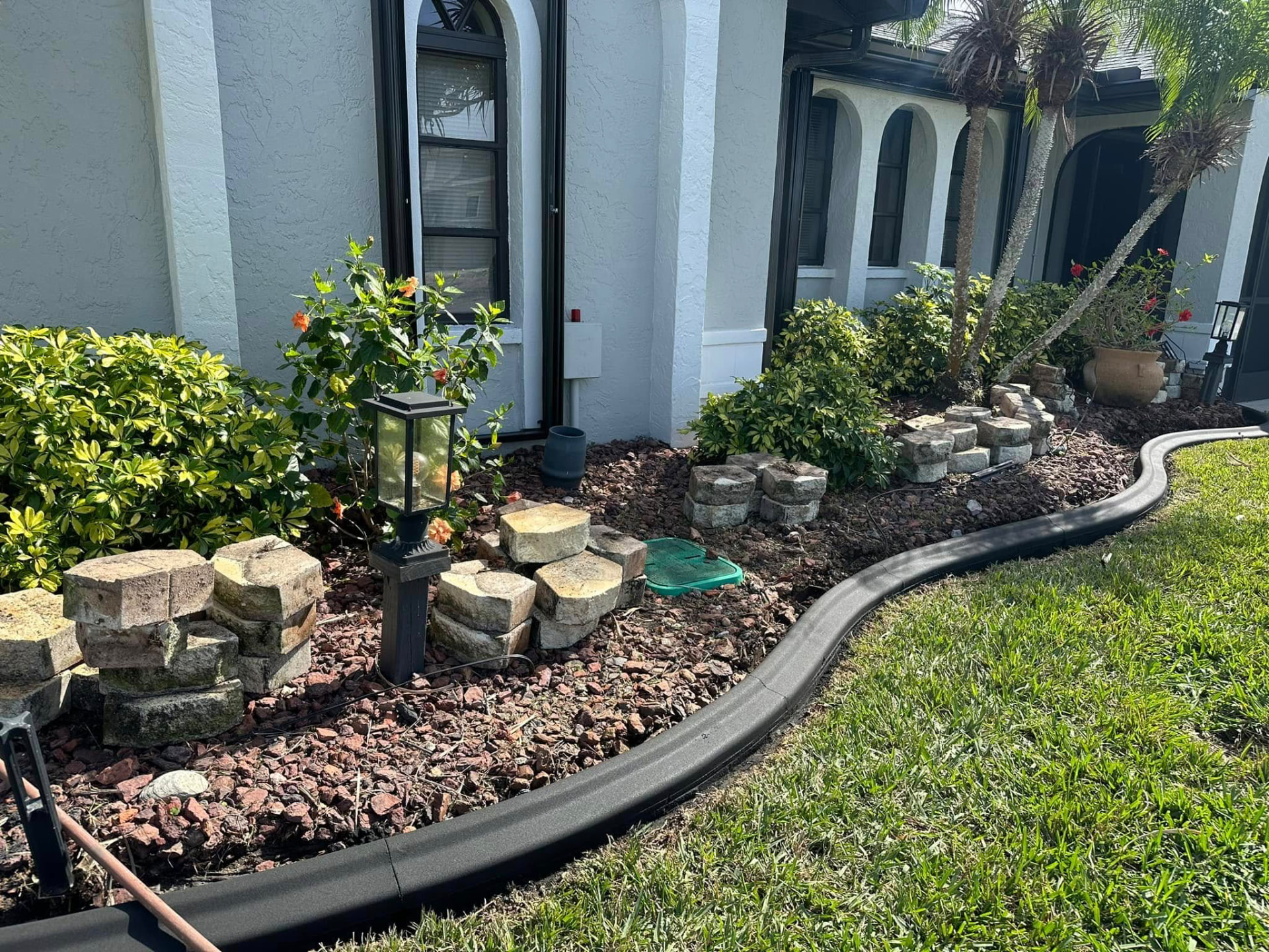 Black curbing along a lava rock bed with coral stone accents