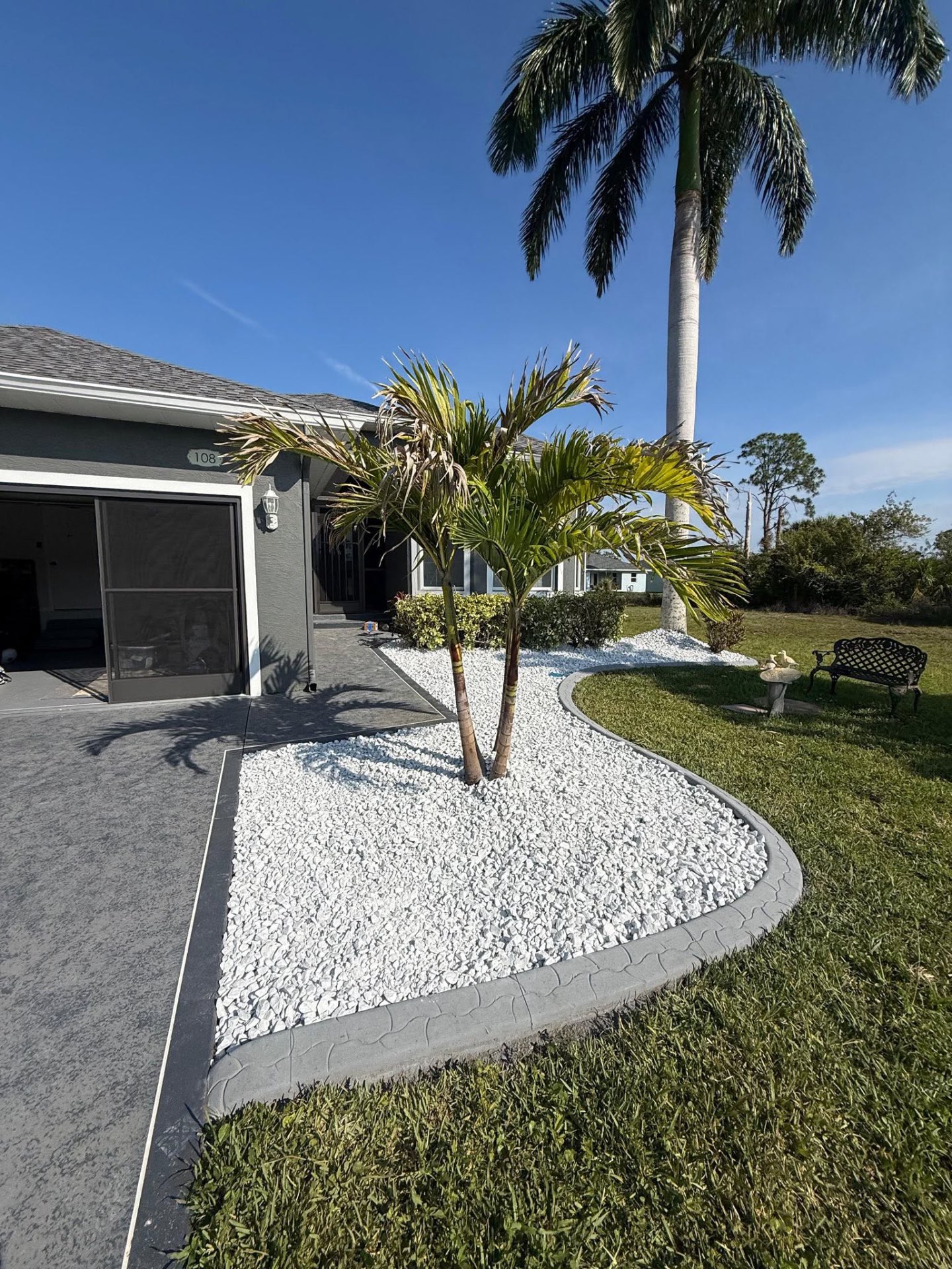 White rock garden with curbing and palm