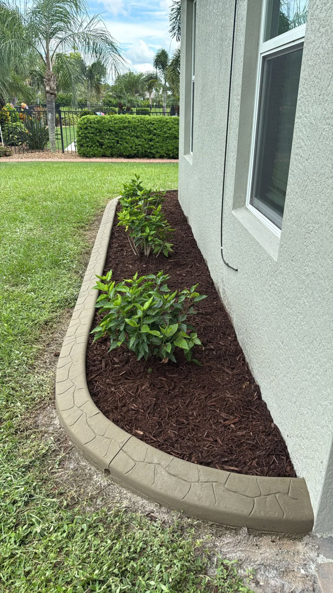 Tan flagstone-pattern curbing along a fresh mulch bed beside a home
